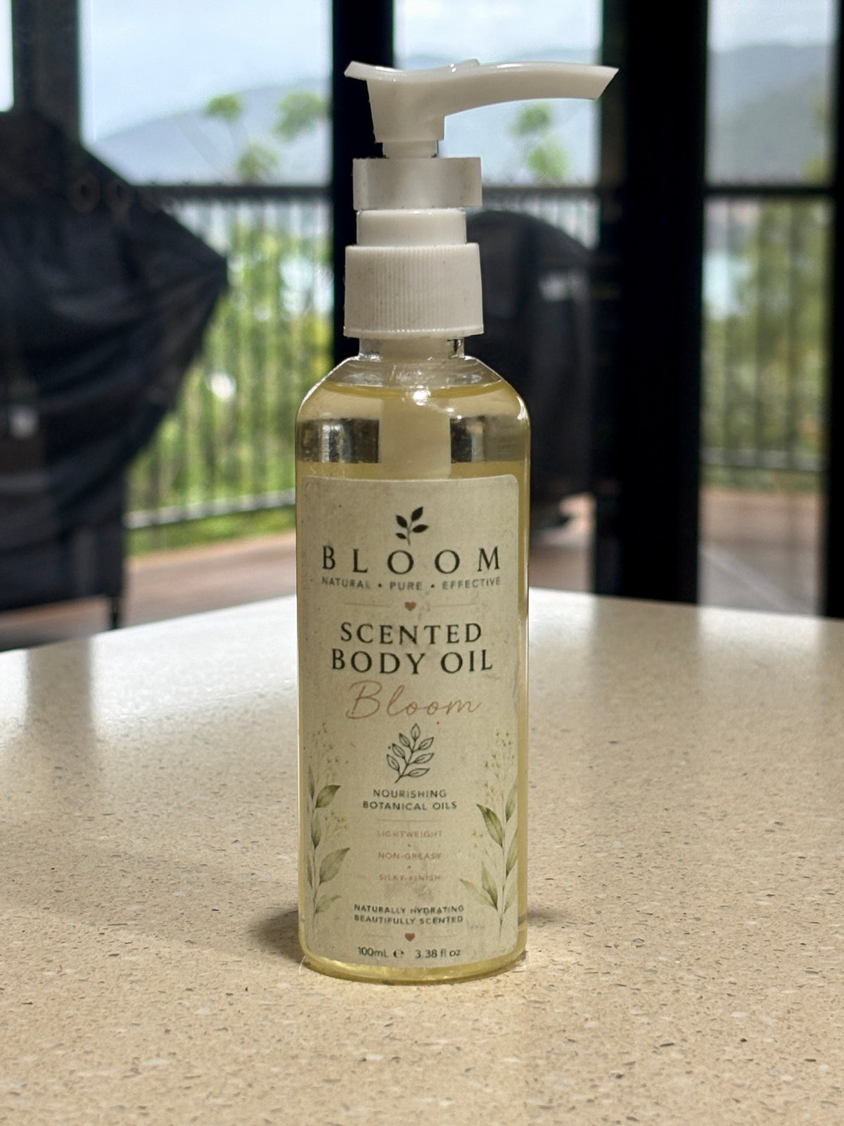 Bloom Botanical Body Oil 100 mL with white pump and botanical label photographed on a countertop