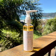 Si Bella scented body oil 100 mL with white pump on a timber railing overlooking Airlie Beach