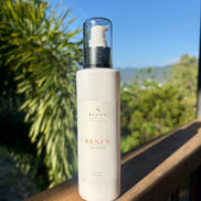 Bloom Organics Renew Cleanser, 200 mL pump bottle on a wooden railing with greenery behind it.