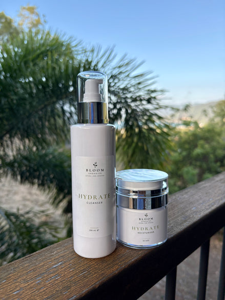 Hydrate Cleanser and Moisturiser on a timber railing with tropical foliage