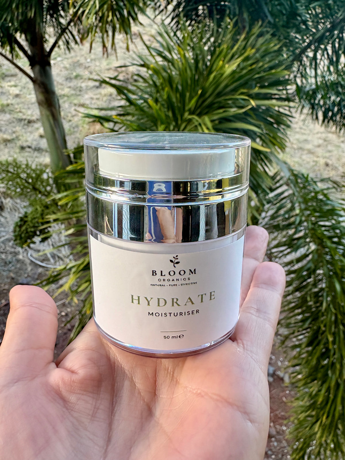 Hydrate Moisturiser 50 mL held in a hand outdoors