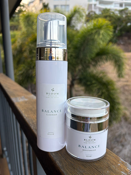 Balance Cleanser and Moisturiser on a timber railing with tropical foliage