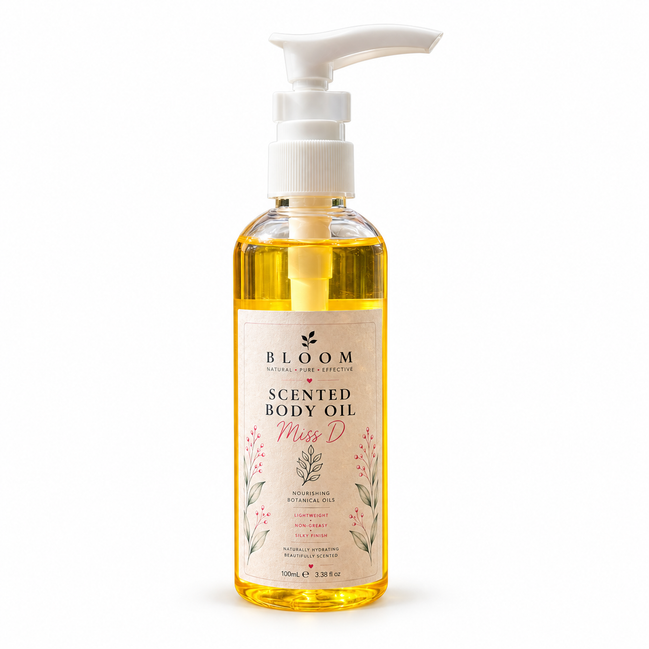 Miss D scented body oil 100 mL in a clear bottle with white pump and golden oil on a white background