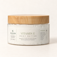 Bloom Organics Vitamin E Body Butter, 100 g glass jar with bamboo lid on a warm ivory-white background.