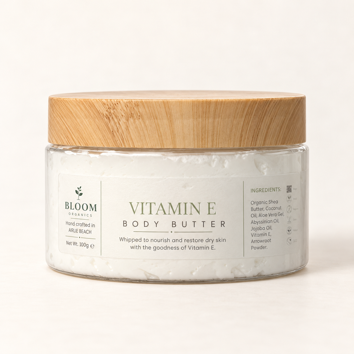 Bloom Organics Vitamin E Body Butter, 100 g glass jar with bamboo lid on a warm ivory-white background.