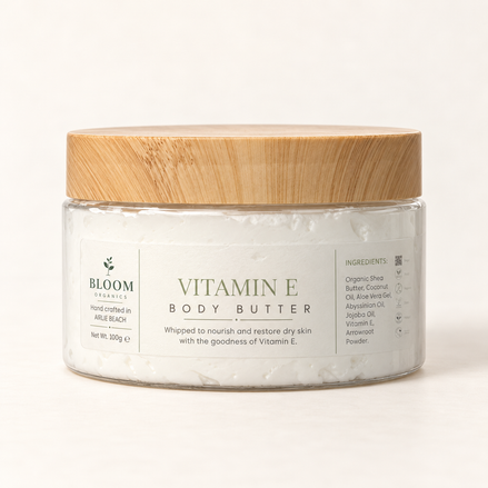 Bloom Organics Vitamin E Body Butter, 100 g glass jar with bamboo lid on a warm ivory-white background.